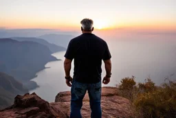 a brawny man with grey hair views sunset from a cliff