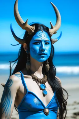 A photo of a blue skin asian goddess with painted blue face and body skin, wavy black hair deer antler horns, standing on a sunny beach