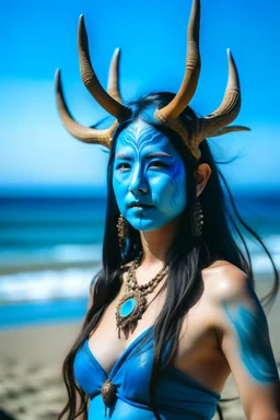 A photo of a blue skin asian goddess with painted blue face and body skin, wavy black hair deer antler horns, standing on a sunny beach