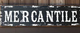 fill composition with large and wide historical hand painted old western sign that reads: "MERCANTILE" white on black with inset white stripe boarder aged paint on wood sanserif