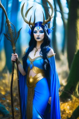 A picture of a beautiful blue faced Korean goddess with skin painted blue, blue body, blue torso, wild black hair, stag antlers, elven ears, golden skirt, holding a staff in a sunny forrest