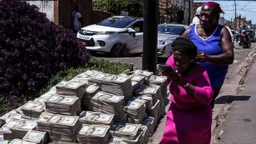 woman hands the bundles of cash her mobile phone provider's located across the street from a high crime area