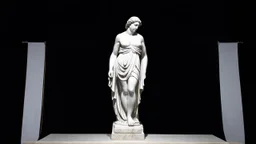 A white marble statue of a draped figure against a black velvet backdrop, illuminated by a single, dramatic spotlight.