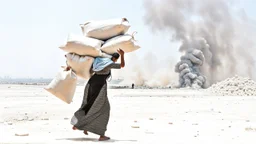 A Palestinian woman wearing a dress carrying very large bags of flour on her back, bending her back down in the destroyed Gaza City, and aid boxes descending from planes near the sea, with a large number of children looking up.