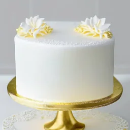 A picture of a simple white cake with golden decoration