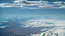 snow peaked rocky mountains with green plain below