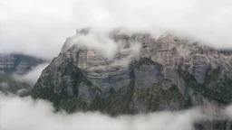 a massive sheer mountain cliff scaling vertically into the sky, partially obscured by dense clouds and mist. the borders — top, bottom, left, and right — fade smoothly into thick fog, while the center reveals the steep, rocky cliff face with fine texture and detail. atmospheric lighting, cinematic composition, natural colors, high contrast between fog and stone.