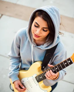 attractive woman wearing a hoodie and playing an electric guitar at high angle