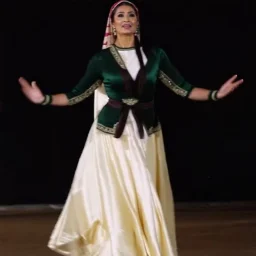 A graceful Azerbaijani female traditional dancer performing a famous Azerbaijani folk dance. She is wearing a beautiful traditional Azerbaijani dance costume: a long flowing silk dress with rich embroidery, wide skirt, and a colorful kelaghayi (traditional Azerbaijani silk headscarf) covering her head. The dancer moves elegantly with soft hand gestures, delicate finger movements, and smooth spinning steps typical of Azerbaijani women’s dances. The atmosphere is festive and cultural, with traditi