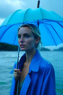 In the music video, a 23-year-old woman with blonde hair and bright blue eyes stands in the sea, se has a bun.. She holds an umbrella, but it offers no protection from the pouring rain. The rain pours through the umbrella, it is leaking and makes staines. The rain under the umbrella is heavy paint petrol blue, the rain transforms through the umbrella. She is painted blue because of the blue rain drops. The rain is pouring heavily. She is standing in the middle of the sea. the raindrops are paint