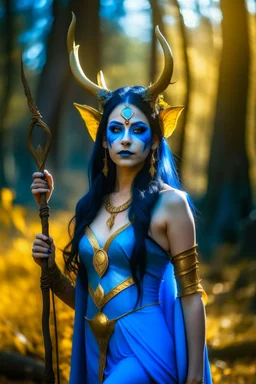 A picture of a beautiful blue faced Indian goddess with skin painted blue, blue body, blue torso, wild black hair, stag antlers, elven ears, golden skirt, holding a staff in a sunny forrest