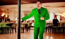 man in a green suit in a restaurant with purple lights, dancing on a pole