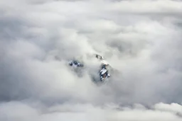 large scale, far away. a massive sheer snowy mountain cliff with very sparse vegetation scaling vertically into the sky, partially obscured by dense clouds(color d0d1d5) and mist. the borders — top, bottom, left, and right — fade smoothly into thick fog, while the center reveals the steep, far away rocky cliff face with fine texture and detail. atmospheric lighting, cinematic composition, natural colors, high contrast between fog and stone. photography