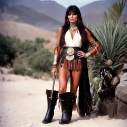 youthful Caroline Munro in a native outfit, she wears leather boots