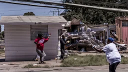 woman hands the bundles of cash her mobile phone provider's located across the street from an boarded up liquor store