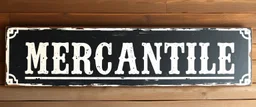 fill composition with large and wide hand painted old western sign that reads: "MERCANTILE" white on black with inset white stripe aged paint sanserif