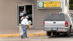 woman hands the bundles of cash her mobile phone provider's located across the street from an boarded up liquor store