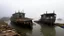 Placeholder: Two old, rusty barges sit on a still sea under a heavy, overcast sky; stilt houses loom ominously in the background, shrouded in a thick, gray mist.