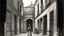 Placeholder: Illustration of a courtyard with a female figure, rendered in a rough, textured style reminiscent of charcoal or pastel drawings. The color palette is predominantly monochromatic, with shades of gray and hints of muted colors. The courtyard is enclosed by buildings with simple, geometric shapes and rough, weathered surfaces. There are several windows and a doorway visible, each framed with dark outlines. The ground is paved with irregular stones, adding to the textured feel of the scene. A slend
