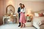 Placeholder: very beautiful lady with beautiful midi skirt and blouse standing next to her couple in a luxury bedroom with high heels next to makeup desk looking to camera
