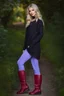 Placeholder: beautiful 18 year old girl with ash blonde hair and blue eyes with her curvy hair down, wearing a long-sleeved woollen top, and lilac long leggings, with long red boots full body shot