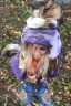 Placeholder: blonde taking selfie.thick thighs,thick calves,flat belly,curvy fell. big head. Mantle is sewed of upcycled Denim and sewed together of camouflage pieces. Pieces' color are orange, cream and purple. It is with big bright purple felt tippet and birght-colored-hood is merged with colorful beanie. Big colored headphones (gold rings!) is merged with small felt cap with small visor. Style: Haute Couture in 1950's Brazil, N.Y.C fashion in 2023