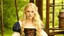 Placeholder: Photo is in sharp focus with high resolution and is a closeup of a beautiful and slender caucasian 17 year old teen girl with long wavy platinum blonde hair. She is wearing a medieval peasant dress with a corset. She is seated at a spinning wheel gazing at the viewer.