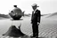 Placeholder: imitating analog photography in black and white, man with a fish tank instead of a head, three-piece suit, in a desert, realism, white and black photographic
