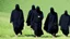 Placeholder: Black robed, hooded monks in the field