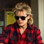 Placeholder: 2/3 Roddy Piper from 1988 wearing black shades, lumberjack red and black button-down shirt, mullet, movie still from 'They Live' movie, matte oil painting