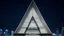 Placeholder: Skyscraper shaped like the letter 'A', with steel diagonal beams and a massive triangular atrium at its core, glowing at night.