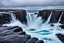 Placeholder: massive intimidating rock cliffs ascend all around and further up out of view. far below, the stormy ocean swirls intimidatingly. The ocean water falls off a waterfall down into a circular pit