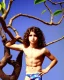 Placeholder: beautiful 12 year old arabic boy with long, curly hair and light blue eyes,shirtless, in front of a distant mango tree, speedos