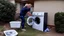 Placeholder: married couple drains water out of household washing machine