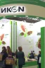 Placeholder: Corner green exhibition stand of a food company with product displays and a meeting area