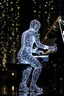 Placeholder: The whole body of Maniquí de glassy filled with tiny sparkling lights in the background Artist mader playing the piano