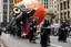 Placeholder: 200 ft tall cartoonish jesus parade balloon pulled by multiple grim reapers, multi colored, bright, vivid, psychedelic, high detailed, high gloss, insanely detailed, matte, horrorcore, lining the street, unsettling contrast, monument to death, live action shot grim reaper parade, pulling a jesus parade float