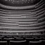 Placeholder: a close up view from stage of a single chair on stage under spotlight at a dark and empty symphony hall