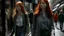 Placeholder: shoulder-length red-haired woman walking along a street full of shops, with a translucent woman following her