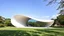 Placeholder: A large, elliptical-shaped pavilion set in the middle of a tranquil park. The building's sleek, continuous curve hugs the earth, with an elliptical glass roof that reflects the sky and surrounding nature. The smooth lines of the structure create a calming flow, and its minimalistic design emphasizes organic shapes inspired by natural curves. Award-winning photograph.