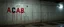 Placeholder: background of firing squad execution wall(wet textured concrete, gray, old, cracked, billet holes, blood stained, 1 wall light) from underground parking, german style, a large blocky upside down "A.C.A.B." painted on left(old faded paint, red stains running down and past), cyberpunk,