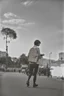 Placeholder: a student girl ,short hair with her books in her hand walking in street,next to trees.