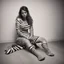 Placeholder: This is not a creature. It is a consequence: she is sitting down on the floor in zebra, showing off her sandals