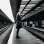 Placeholder: A young German woman with long hair and a black trench coat longingly waiting for her lover at a train station in Munich