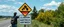 Placeholder: roadside sign warning about dangerous illusions and artwork in the road, people pointing at the sign, it has some beautiful neon artwork