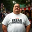 Placeholder: a little fat swedish man standing on a busy street wearing a t-shirt. a kebab brothers t shirt, with a kebab brothers logo, KEBAB BROTHER tattoo in forehead