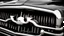 Placeholder: Photograph of a the front grill of a gorgeous, expensive, oldschool black muscle car with a big, black front grill, realistic, stylish, taken up close from the front of the car.