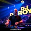 Placeholder: A dj on a night rave club standing mixing songs , he looks like Bryan Cranston kinda, bald with beard. strobes and blue yellow light, a big sign with "DJ ROY" in the background, this is a album cover for his dj roy essentials album.