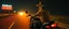 Placeholder: The kebab man driving fast on his motorcycle, fire from the exhaust, widescreen picture, empty road on the country at night, comic style, no helmet and he have a long black beard, neon kebab signs along the road, jesus at his cross