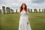 Placeholder: A tall slim red-headed woman, in a white floaty dress, standing in front of Stonehenge